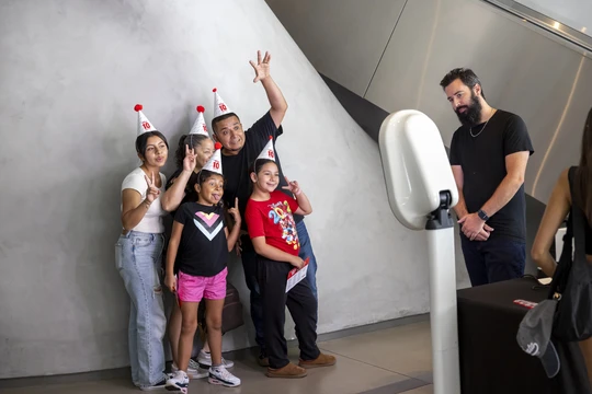 A family at The Broad taking a photobooth photo in Broad 10 party hats
