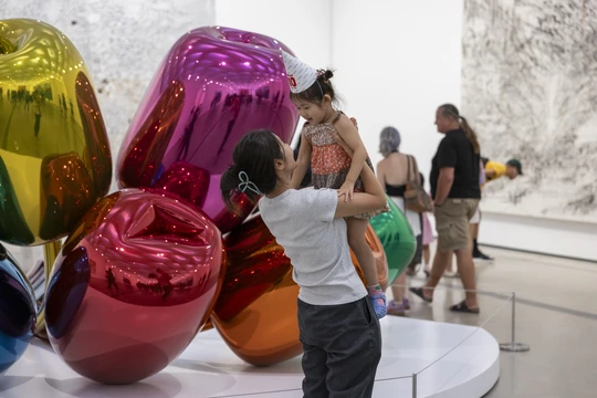 Parent holding a baby in front of Jeff Koons' Tulips sculpture at The Broad