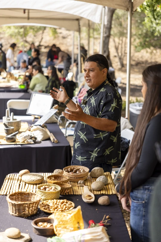 Man and woman at a basket weaving booth speaking out to an audience