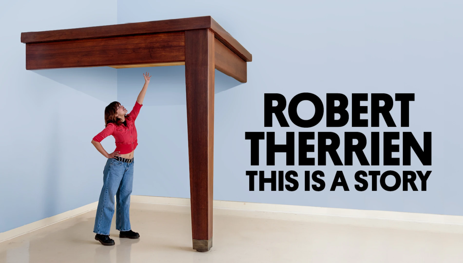 A young woman reaching for a sculpture of an oversized dining table that she can't quite reach next to the exhibition title "Robert Therrien: This is a Story"